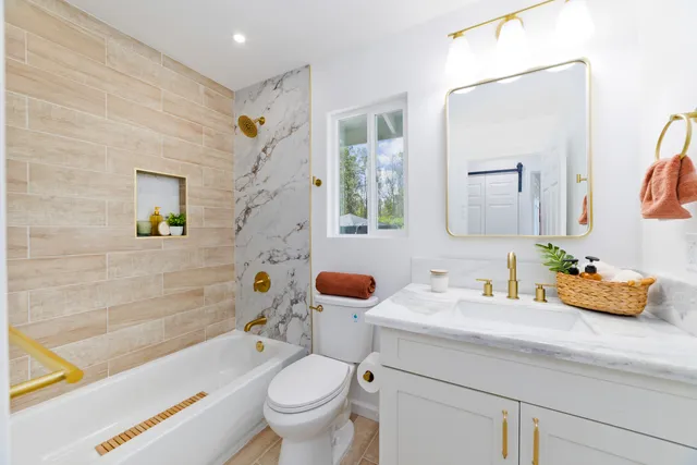 a bathroom with a granite countertop sink mirror toilet and bathtub
