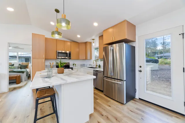 a kitchen with granite countertop a refrigerator a stove a sink a center island and wooden floor