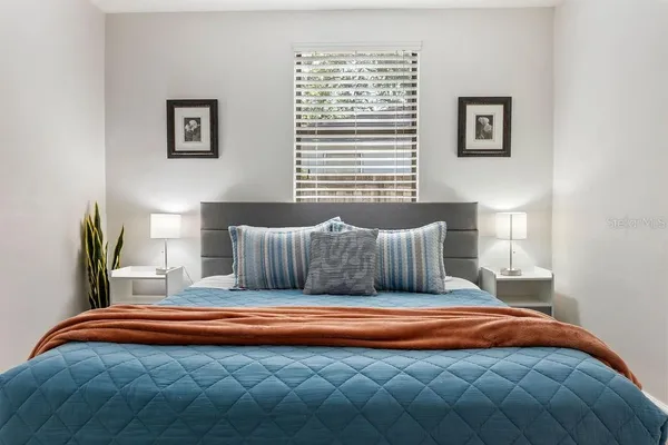 a bedroom with a bed and a lamp next to a window
