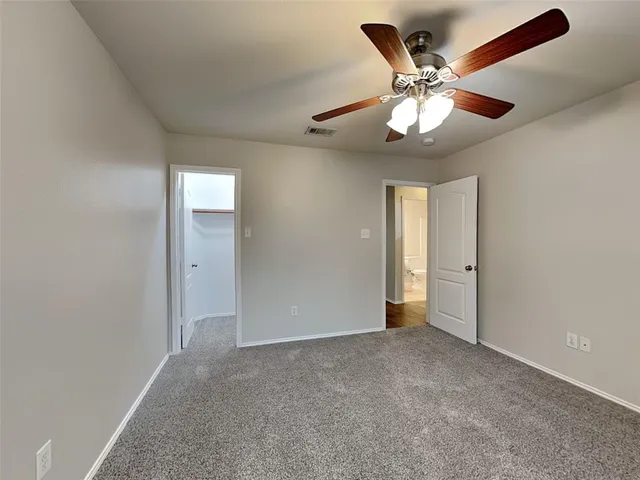 a view of an empty room and chandelier fan