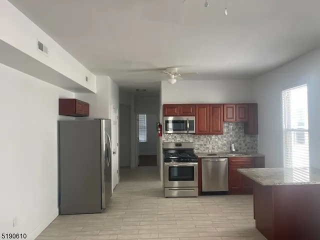 a kitchen with stainless steel appliances kitchen island granite countertop a refrigerator and a stove top oven