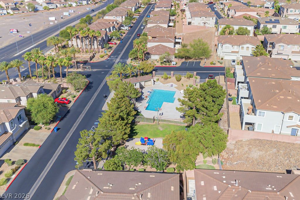754 Solitude Point Avenue Henderson, NV 89012 - Photo 6 of 38 An aerial perspective showcases a vibrant community pool and playful playground, framed by verdant trees and surrounding residential homes.