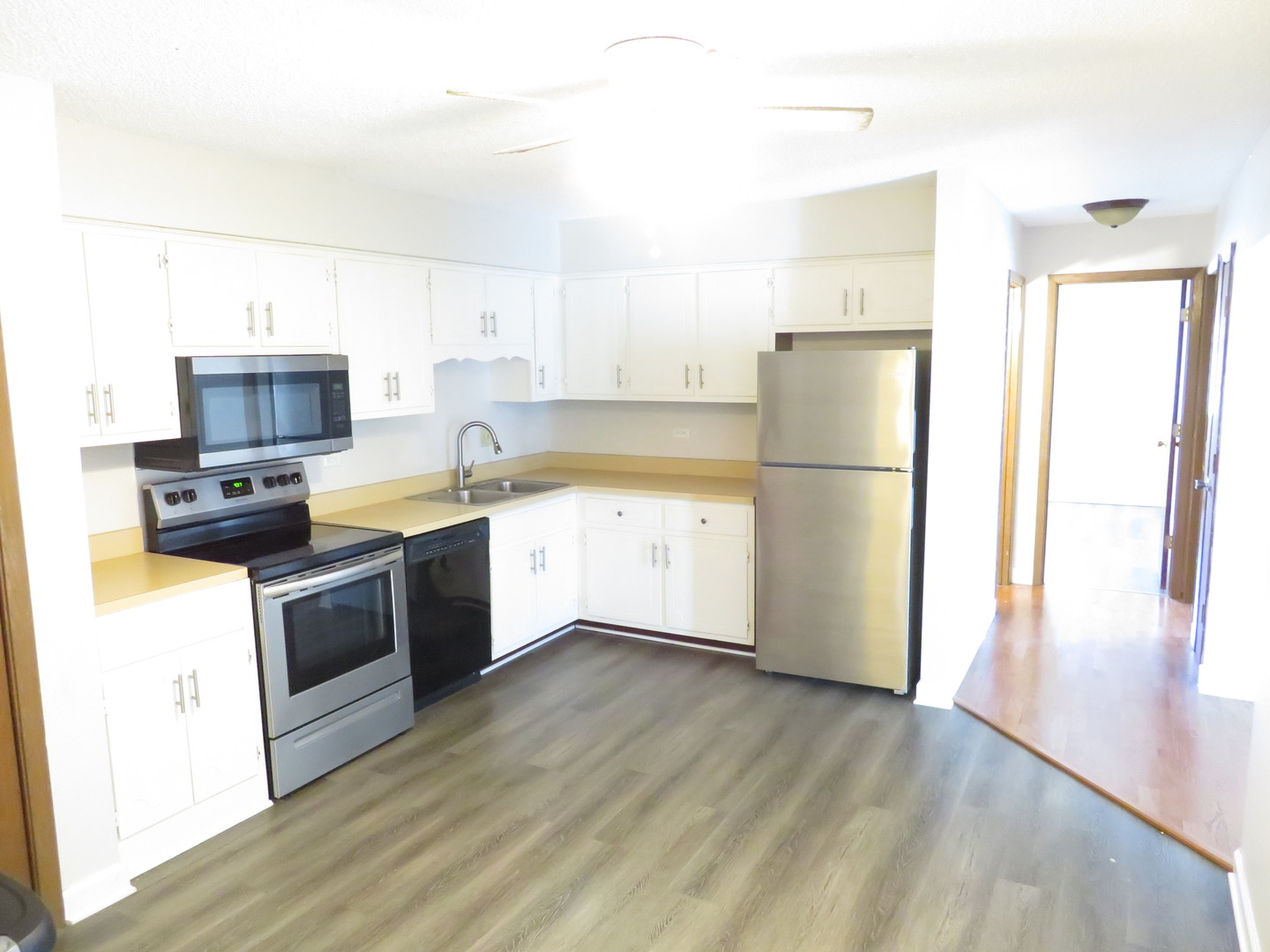 216 Madison Street, Unit 3C Joliet, IL 60435 - Photo 2 of 10 a kitchen with a sink a refrigerator a microwave and cabinets