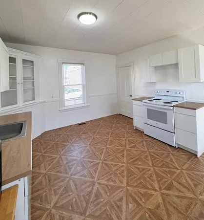 a kitchen with granite countertop a stove a sink and white cabinets