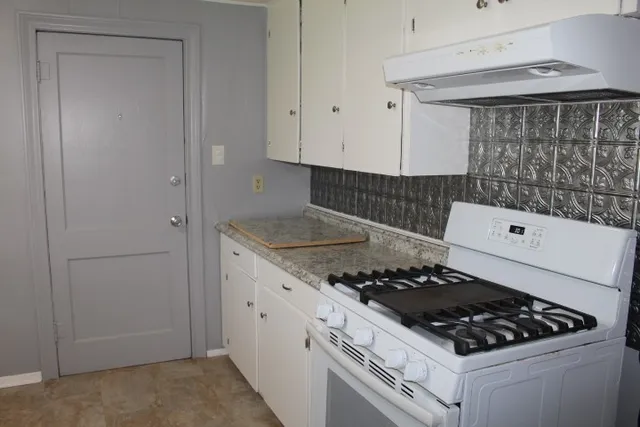 a white stove top oven sitting inside of a kitchen