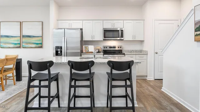 a kitchen with stainless steel appliances a dining table chairs microwave and sink