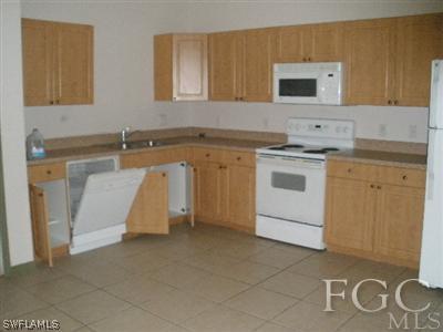 4713 28th Street Southwest Lehigh Acres, FL 33973 - Photo 6 of 8 a kitchen with a sink stove and cabinets