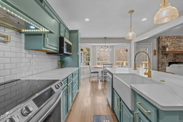 a kitchen with stainless steel appliances granite countertop a sink a stove and a wooden floors
