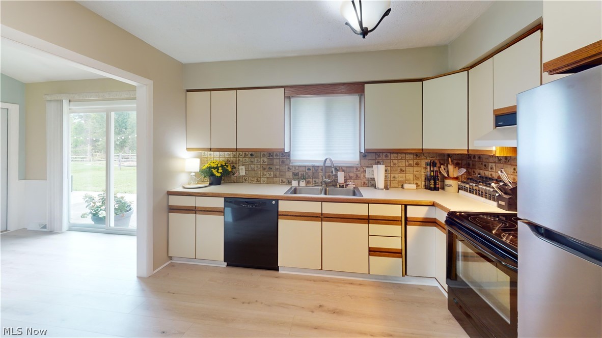 9260 Avery Road Broadview Heights, OH 44147 - Photo 14 of 43 Kitchen featuring wood-finish flooring, light-toned cabinetry with wood trim, a tiled backsplash, and stainless steel appliances