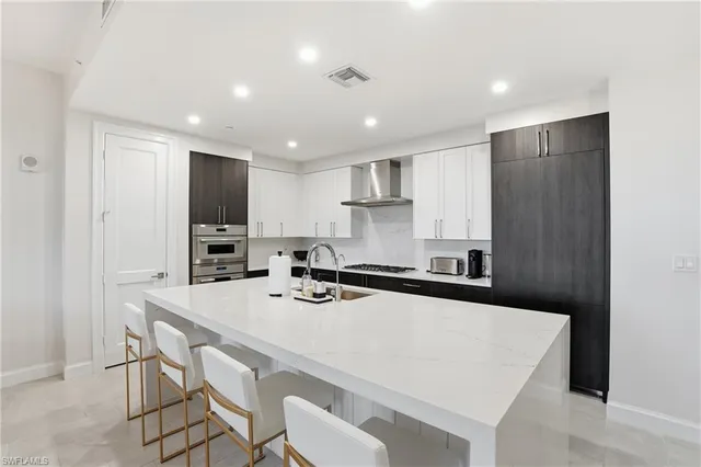 a kitchen with a sink a stove a refrigerator a kitchen island and chairs