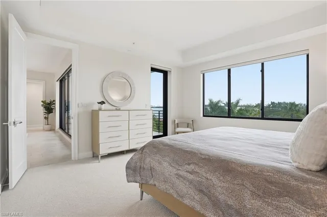 a bedroom with a bed a mirror on dresser and a large window