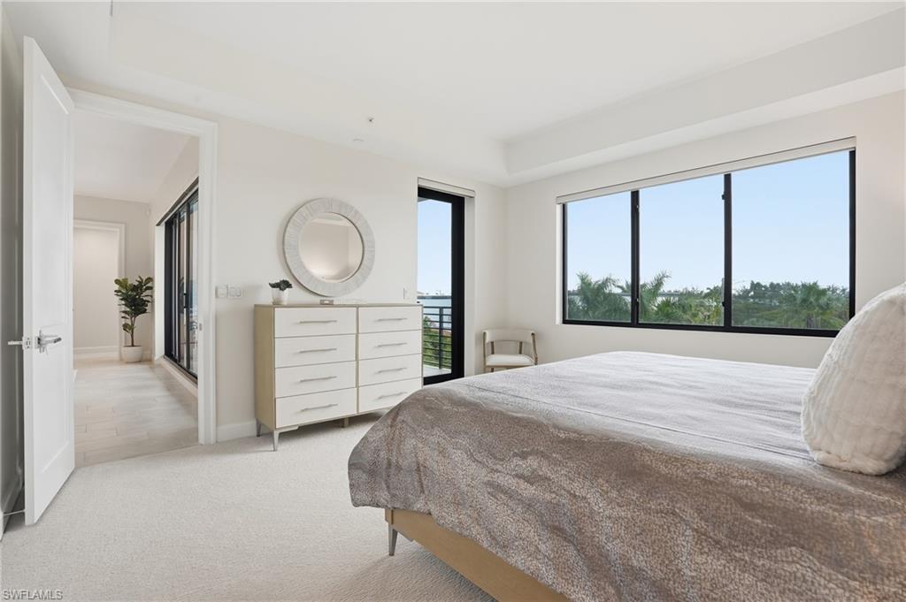 1125 Central Avenue, Unit 469 Naples, FL 34102 - Photo 21 of 38 a bedroom with a bed a mirror on dresser and a large window