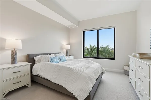 a bedroom with a bed and a dresser next to a window