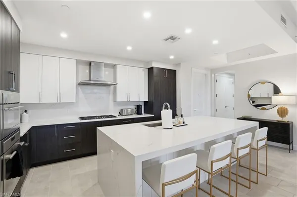 a kitchen with a stove a sink a kitchen island and chairs