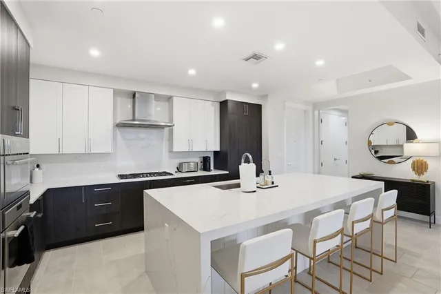 a kitchen with a stove a sink a kitchen island and chairs