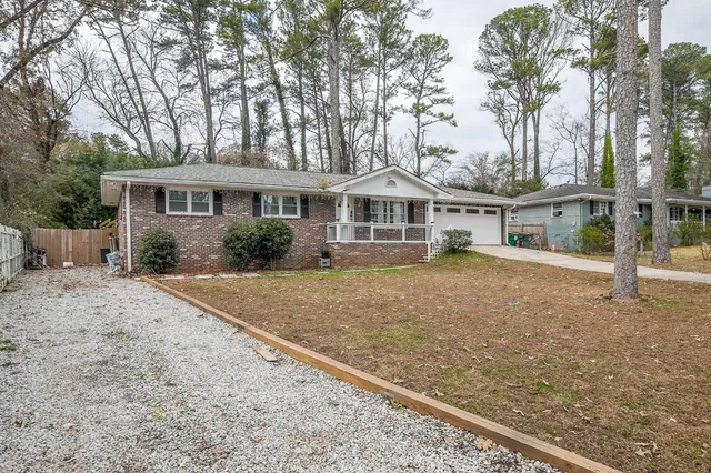 a front view of a house with a garden and trees
