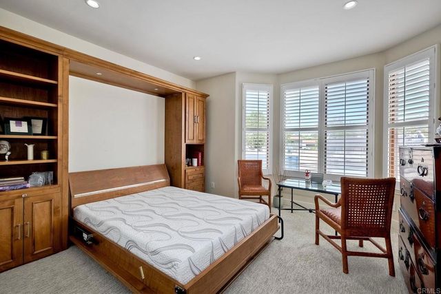 a bedroom with a bed table and a large window