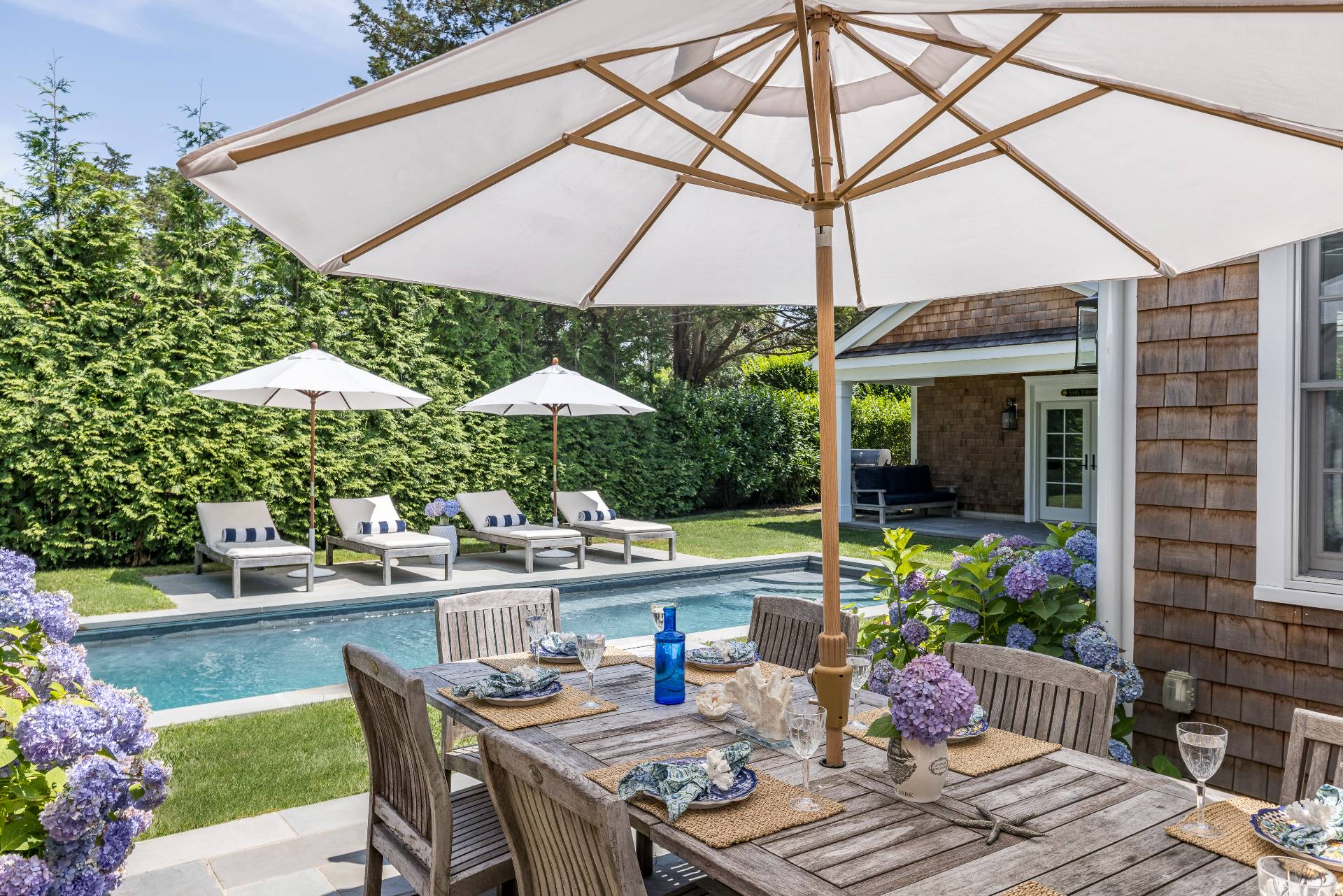 29 Cornell Road Sag Harbor, NY 11963 - Photo 20 of 26 a patio with a table and chairs under an umbrella