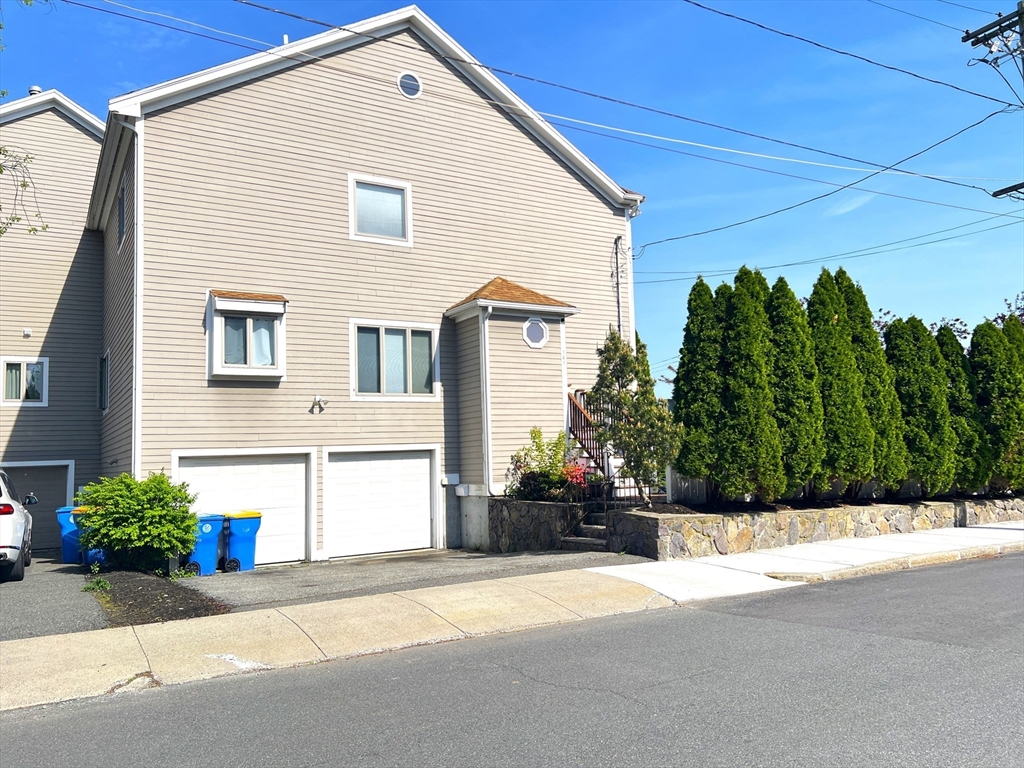 141 Grovers Avenue, Unit 141 Winthrop, MA 02152 - Photo 19 of 21 a front view of a house with a yard and a garage