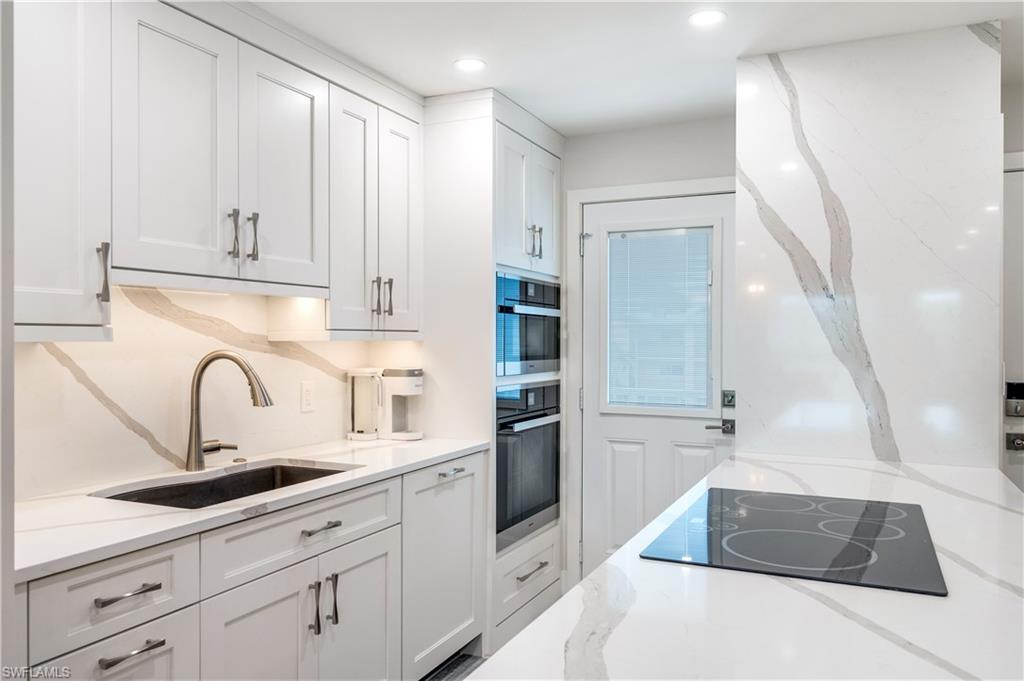 1021 3rd Street South, Unit 310 Naples, FL 34102 - Photo 3 of 27 Kitchen with light stone countertops, white cabinetry, black electric cooktop, stainless steel double oven, and recessed lighting