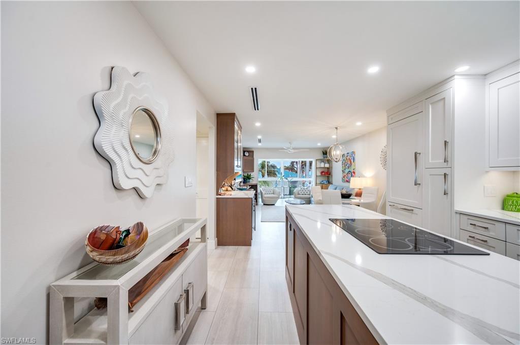 1021 3rd Street South, Unit 310 Naples, FL 34102 - Photo 27 of 27 Kitchen featuring open floor plan, decorative light fixtures, light stone counters, black electric cooktop, and recessed lighting