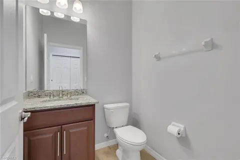 a bathroom with a granite countertop sink vanity mirror and toilet