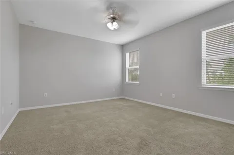 an empty room with windows and ceiling fan