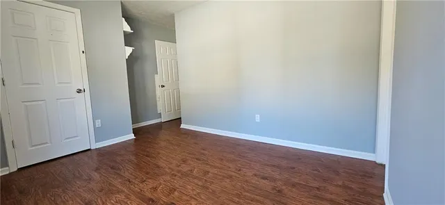 a view of an empty room with closet and wooden floor