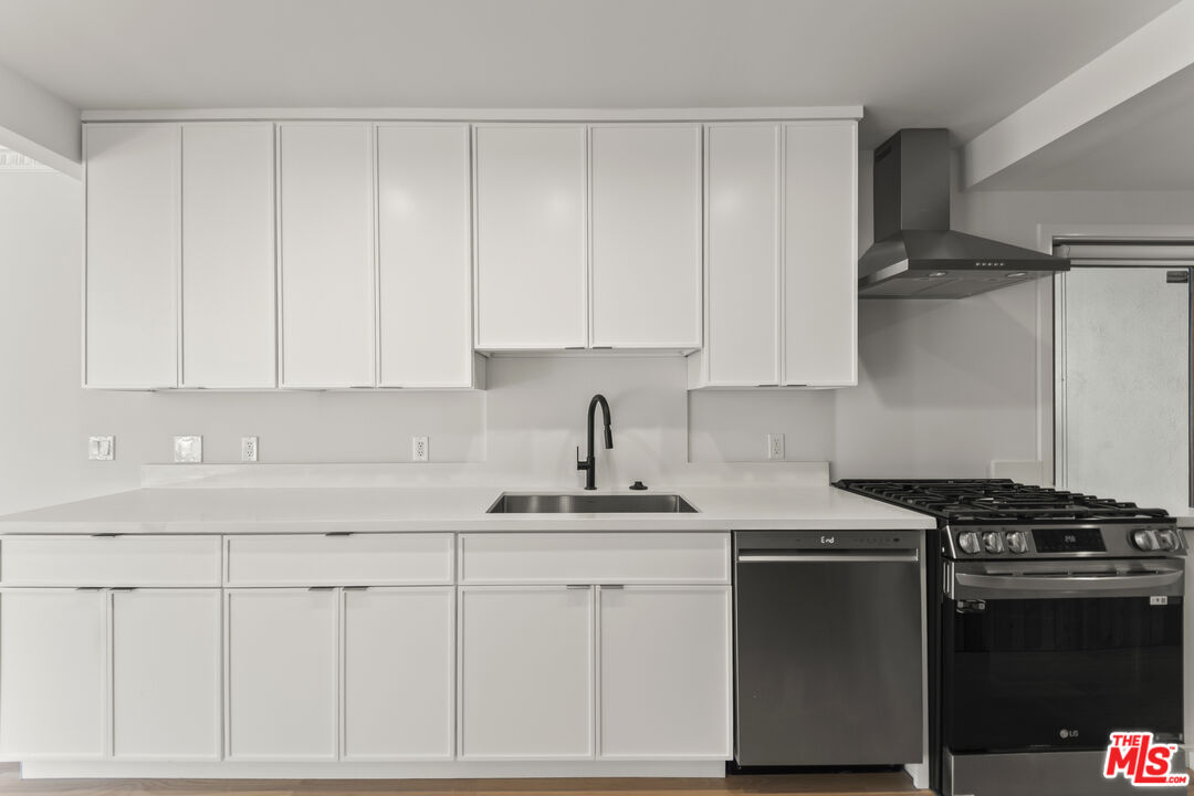 751 18th Street, Unit B Santa Monica, CA 90403 - Photo 7 of 24 a kitchen with white cabinets and appliances