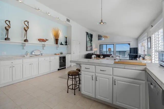 a living room with stainless steel appliances kitchen island granite countertop a table chairs in it and a flat screen tv