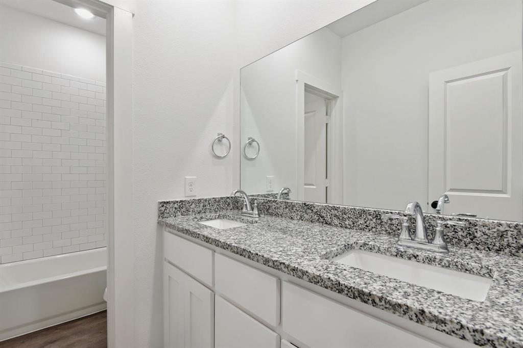 718 West Texas Street Denison, TX 75020 - Photo 12 of 22 a bathroom with a granite countertop sink and a mirror
