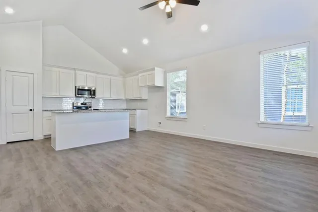 a kitchen with stainless steel appliances granite countertop a stove top oven a sink dishwasher and a refrigerator with wooden floor