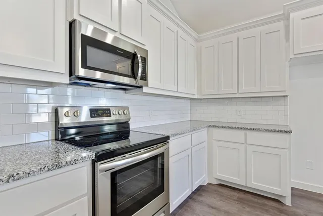 a kitchen with stainless steel appliances granite countertop a sink a stove a refrigerator a microwave and cabinets