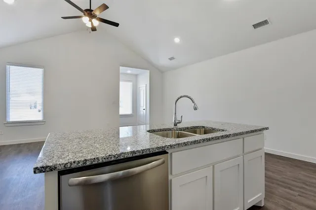 a kitchen with stainless steel appliances granite countertop grey cabinets and a stove top oven