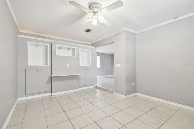 a view of an empty room with window and chandelier fan