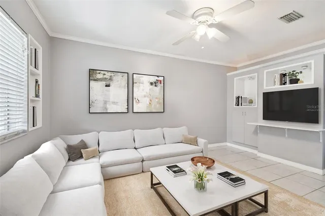 a view of an empty room with window and chandelier fan