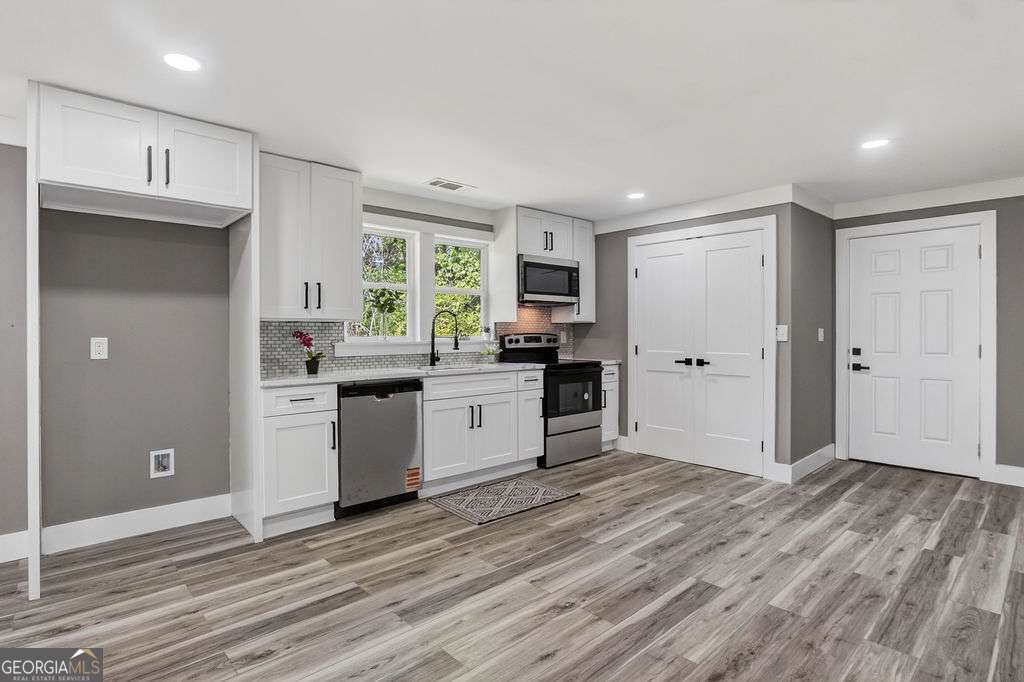 206 Walker Drive Monroe, GA 30655 - Photo 6 of 32 a kitchen with granite countertop a refrigerator and a stove top oven
