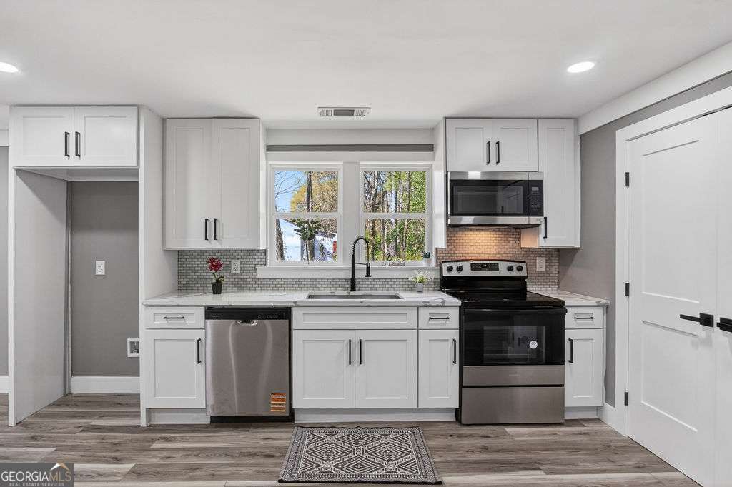 206 Walker Drive Monroe, GA 30655 - Photo 8 of 32 a kitchen with stainless steel appliances a stove sink and cabinets