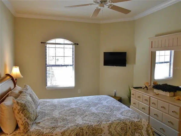 a bedroom with a bed and a flat tv screen on dresser