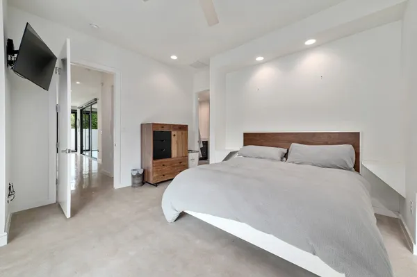 a spacious bedroom with a bed a tv and wooden floor