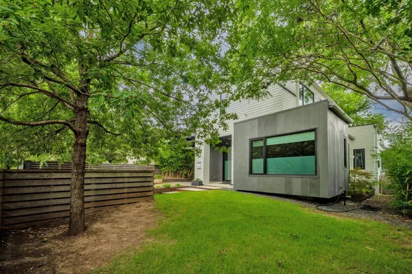 a backyard of a house with large trees and plants