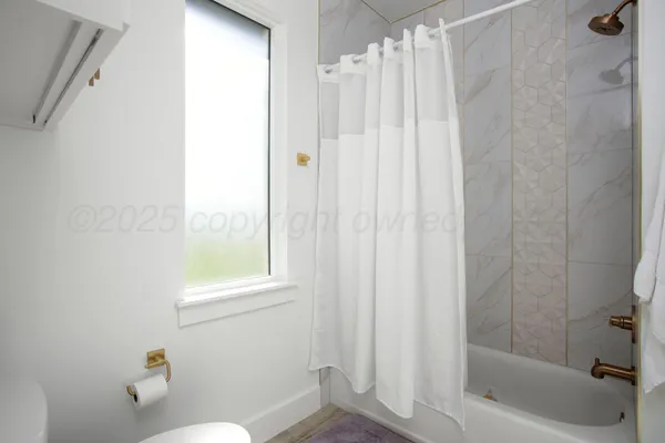 a bathroom with a shower curtain and a window