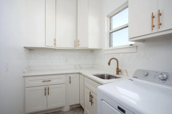 a kitchen with white cabinets and sink
