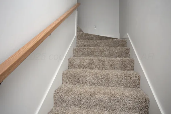 a view of staircase with white walls and white door