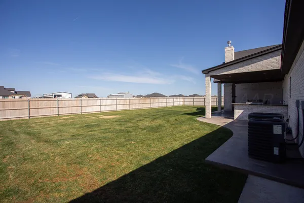 a view of a backyard with lawn chairs fire pit and wooden fence