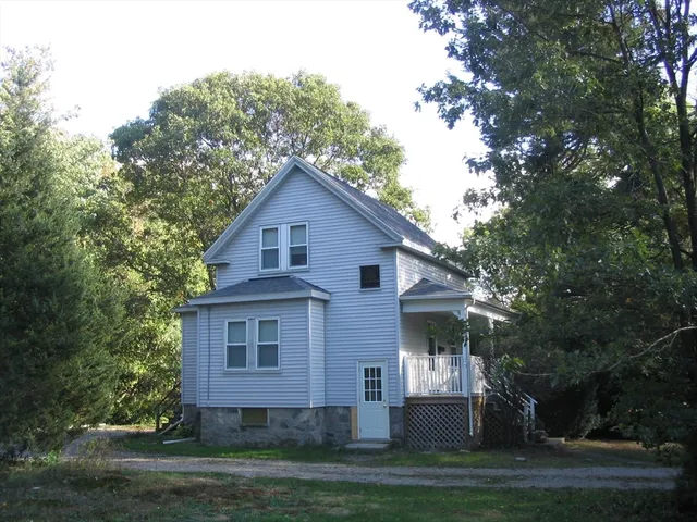 a view of a yard in front of a house with plants and large tree
