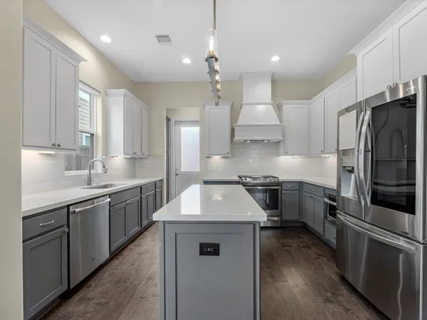 a kitchen with kitchen island stainless steel appliances a sink stove and refrigerator