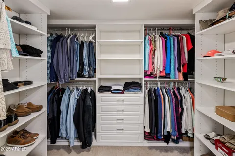 a view of walk in closet with clothes and shoes