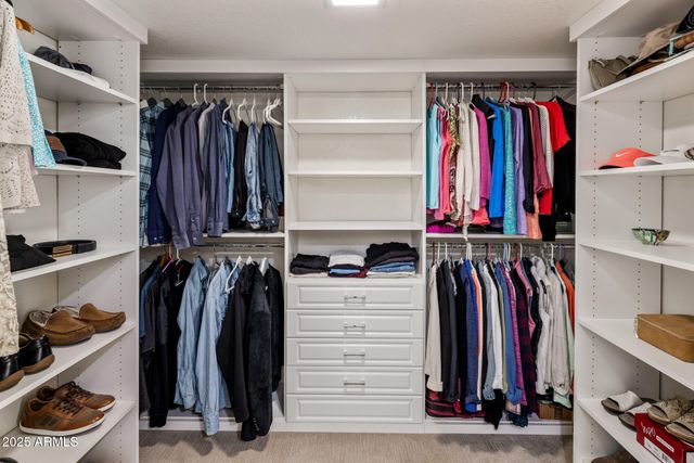 a view of walk in closet with clothes and shoes