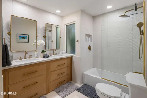 a bathroom with a double vanity sink toilet mirror and bathtub